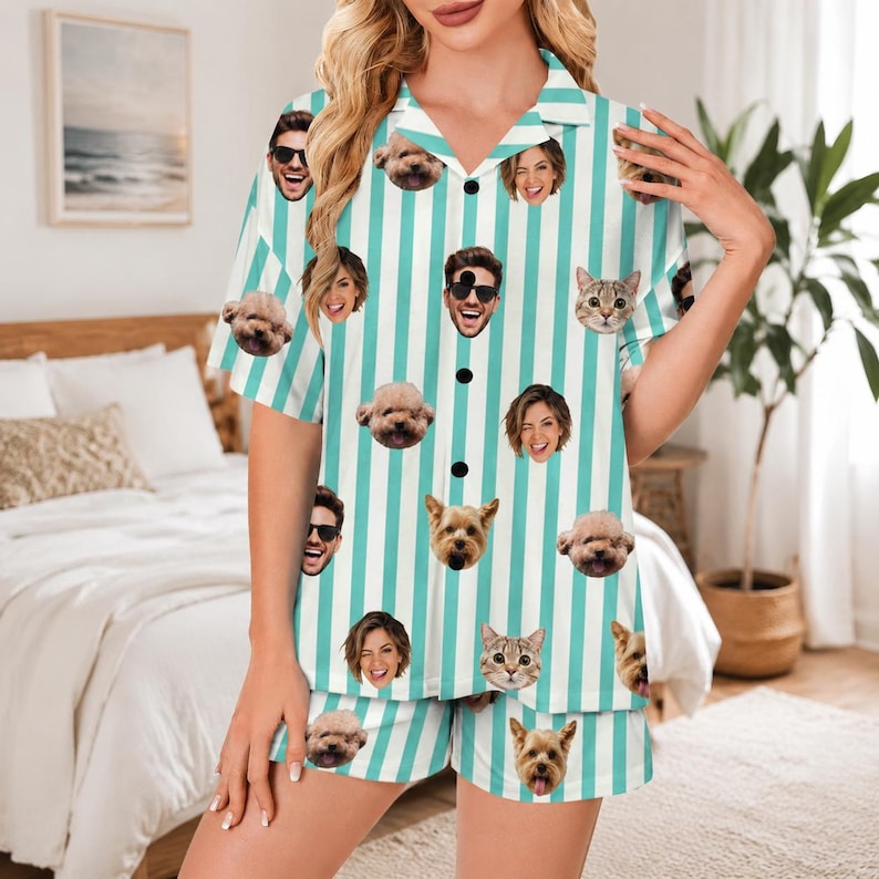 May include: A short-sleeved button-down pajama shirt and matching shorts set featuring a vertical teal and white striped pattern. The fabric is decorated with a repeating print of various human faces and pet dog and cat faces throughout.