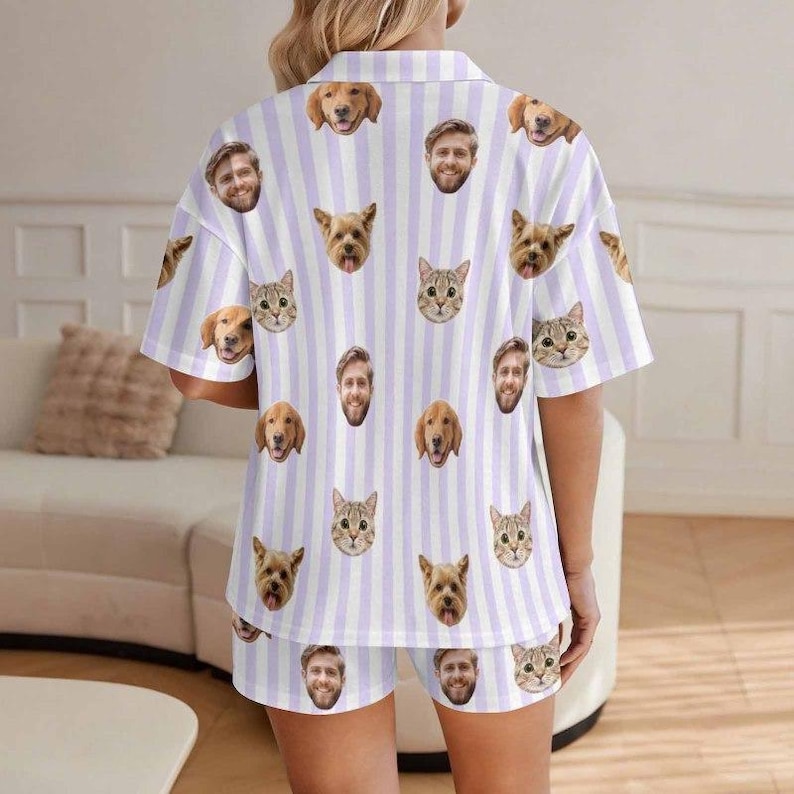 May include: A short-sleeved button-down shirt and matching shorts set featuring a light purple and white vertical striped pattern. The fabric is decorated with a repeating print of various dog and cat faces, along with a man's face.