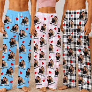 May include: Three pairs of lounge pants featuring repeating photo prints of couples, red heart icons, and the text #MyPerson. The left pair is light blue, the center pair has a pink and white plaid pattern, and the right pair has a black and white plaid pattern.