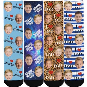 May include: Four pairs of socks with personalized designs. One pair says "I love grandpa" with a photo of a child and an older man. Another says "Happy Father's Day" with a child and a man. The third says "I love dad" with a child and a leopard print background. The last pair has blue and white stripes and says "I love dad".