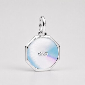 May include: A silver-toned octagonal pendant featuring a smooth, iridescent inlay with swirling pastel blue and purple hues. A small, metallic infinity symbol is centred on the face of the pendant, which is topped with a circular silver-toned bail.