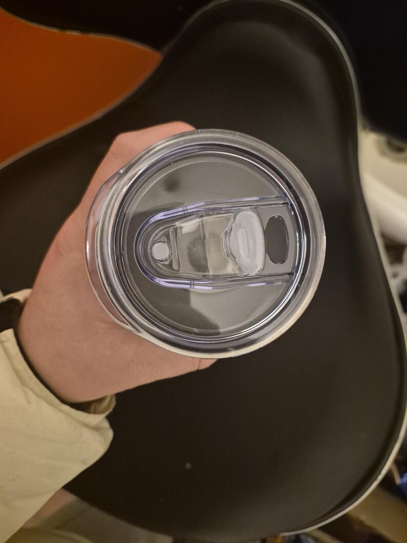 Puede incluir: Una tapa de vaso de pl&aacute;stico transparente con cierre deslizante y una peque&ntilde;a abertura para beber. La tapa es circular y parece estar hecha de pl&aacute;stico duradero. La tapa del vaso est&aacute; dise&ntilde;ada para una taza de viaje o similar.