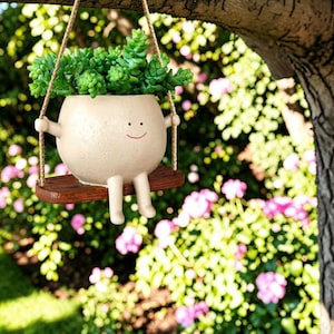 May include: A white ceramic mug with a black handle and the text "But First, Coffee" in a bold, black font. The mug is filled with a dark liquid, likely coffee, and sits on a light-colored surface.