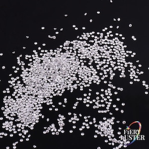 Puede incluir: Una dispersión de pequeños brillantes redondos y transparentes sobre un fondo negro. Los brillantes son reflectantes, captando la luz y creando un efecto brillante. Ideal para proyectos de manualidades y bisutería.