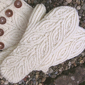 May include: A pair of white knitted mittens with a leaf pattern. The mittens are made with a soft, textured yarn.