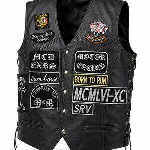 May include: Black leather motorcycle vest with multiple patches. Patches include text such as "STURGIS", "Bonne Nuit Salope", "MCD EXRS", "Motor Cycles", "Born to Run", and "MCMLVI-XC SRV". The vest has a button-up front and lace-up sides.