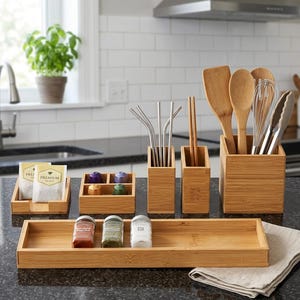 May include: A collection of bamboo kitchen organizers and utensils. Includes a rectangular tray with spice jars, tea bag holders, utensil holders, and a variety of kitchen tools. Stainless steel straws and wooden chopsticks are also visible.