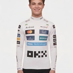 May include: A white long-sleeve mock neck shirt featuring various sponsor logos including Android, McLaren, Cisco, Dell Technologies, and OKX. The garment has a fitted silhouette with multiple brand graphics printed across the chest and sleeves.