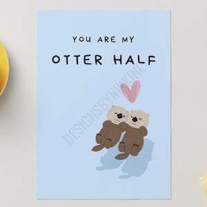 May include: A light blue card with the text "YOU ARE MY OTTER HALF" and two cartoon otters hugging. A pink heart floats above the otters. The card has the watermark "DESIGNSBYNIKKI".