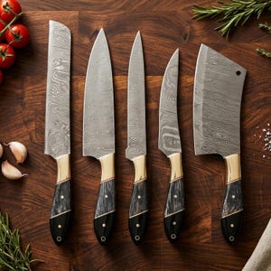 Könnte beinhalten: Ein Set aus fünf Küchenmessern mit gemusterten Stahlklingen und gold-schwarzen Griffen. Die Messer umfassen ein Brotmesser, ein Kochmesser, ein Schälmesser, ein Ausbeinmesser und ein Hackmesser. Die Messer sind auf einem Holzschneidebrett angeordnet.