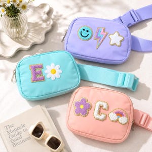 May include: Three rectangular belt bags in light purple, turquoise, and peach. The purple bag features a smiley face, lightning bolt, and star patch. The turquoise bag has a letter E and daisy patch. The peach bag has a flower, letter C, and rainbow.