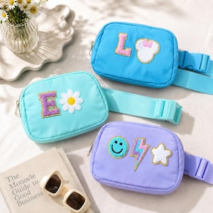 May include: Three belt bags in bright blue, light turquoise, and lavender. The blue bag features a letter L and a white mouse head patch. The turquoise bag has a letter E and a white daisy patch. The lavender bag displays a smiley face, a lightning bolt, and a star patch.