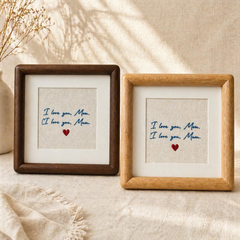 May include: Two square framed artworks with the text "I love you, Mom. I love you, Mum." in blue script, with a red heart. One frame is dark brown, the other is light brown.