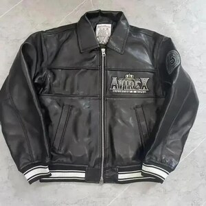 Puede incluir: Chaqueta de cuero negra con cremallera, cuello y pu&ntilde;os y dobladillo a rayas blancas. La chaqueta presenta el logotipo "AVIREX" en el pecho y un parche con el n&uacute;mero "5" en la manga. Un estilo bombardero cl&aacute;sico.