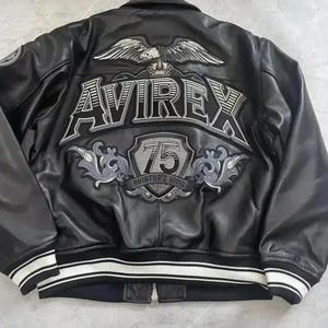 Puede incluir: Chaqueta de cuero negro con pu&ntilde;os y dobladillo a rayas blancas. La parte trasera presenta un gran dise&ntilde;o bordado con la palabra "AVIREX", un emblema de &aacute;guila y el n&uacute;mero "75". La chaqueta tiene cierre de cremallera.