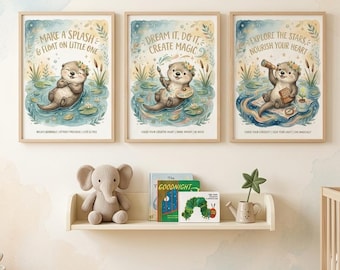 May include: Three framed art prints featuring watercolor illustrations of otters in a whimsical style. Each print has a different otter scene with text: "Make a Splash", "Dream It, Do It", and "Explore the Stars". A shelf below holds a stuffed elephant, books, and a small watering can.