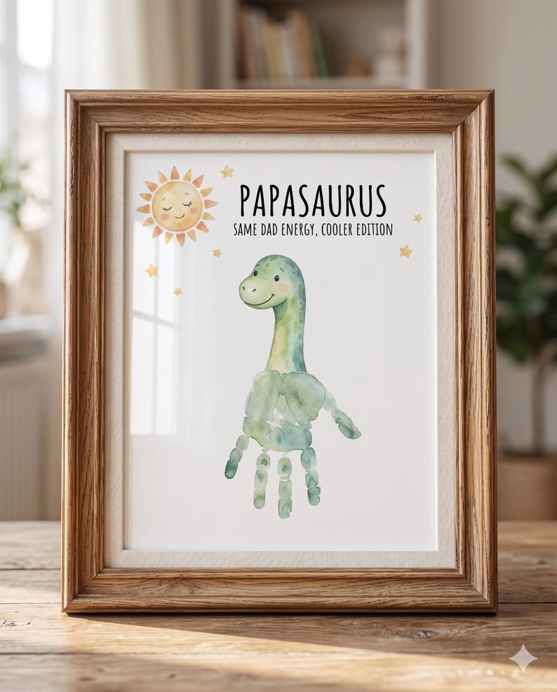 May include: A framed print with a watercolor dinosaur design. The print features a green dinosaur with a handprint body and the text "Papasaurus: Same Dad Energy, Cooler Edition." The frame is made of wood.