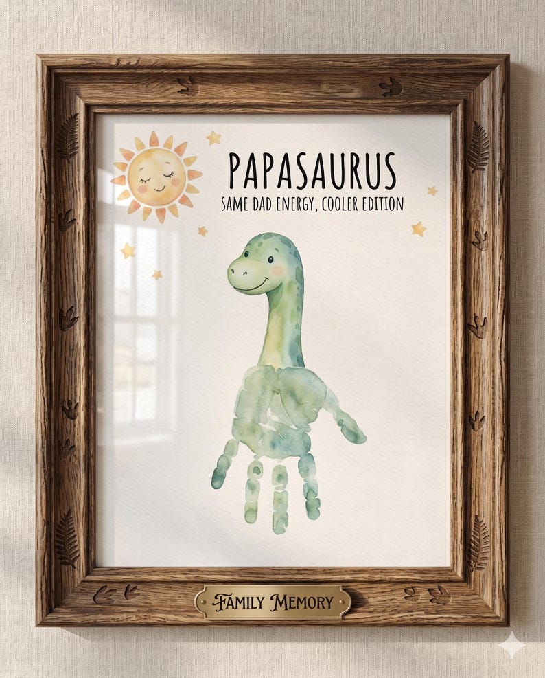 May include: A framed print featuring a watercolor dinosaur made from handprints, with the text "Papasaurus: Same Dad Energy, Cooler Edition." The print includes a smiling sun and stars, with a "Family Memory" plaque.