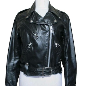 May include: Black leather biker jacket with a notched collar, an off-centre zip, and silver-tone metal hardware. Includes a belted waist, zipped pockets, and press studs on the shoulders and lapels. A classic motorcycle style.