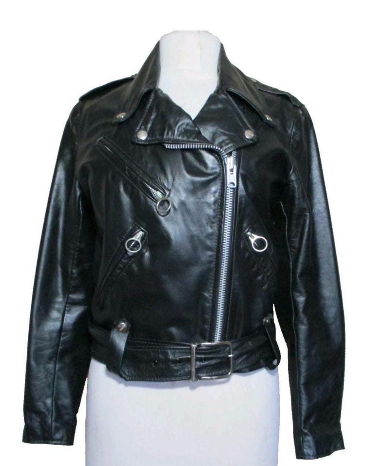 May include: Black leather biker jacket with a notched collar, an off-centre zip, and silver-tone metal hardware. Includes a belted waist, zipped pockets, and press studs on the shoulders and lapels. A classic motorcycle style.