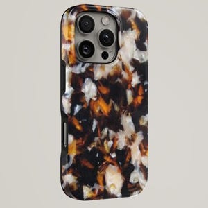 Op de afbeelding: Een smartphonehoesje met een glanzend, meerkleurig schildpadpatroon in tinten donkerbruin, amber en crème. Het hoesje heeft een verhoogde camera-uitsparing met drie zichtbare ronde lenzen en zwarte zijknoppen langs de rand van de behuizing.