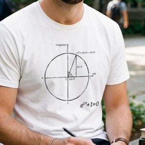 Op de afbeelding: Een wit T-shirt met korte mouwen en een zwarte grafische print van de eenheidscirkel in het complexe vlak. Het ontwerp bevat labels voor de reële en imaginaire assen, goniometrische functies en de vergelijking van Euler e^iπ+1=0.