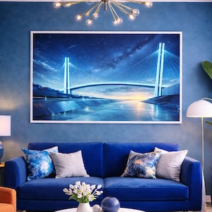 Puede incluir: Un salón moderno con un tema azul. Un sofá azul con cojines decorativos se encuentra frente a una gran obra de arte enmarcada que representa un puente por la noche. Una mesa de centro blanca y una alfombra estampada completan el espacio.