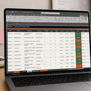 Pu&ograve; includere: Un computer portatile color argento che mostra un foglio di calcolo intitolato Projects - Master Project & Revenue Tracker. Lo schermo visualizza colonne per data, cliente, nome del progetto, tipo di servizio, complessit&agrave; e ricavi.