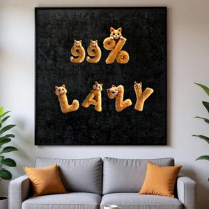 Könnte beinhalten: Ein gerahmtes Kunstwerk zeigt die Wörter "99%" und "LAZY", die aus flauschigen, orangefarbenen Katzenbuchstaben auf einem strukturierten schwarzen Hintergrund gebildet werden. Das Kunstwerk hängt über einem grauen Sofa mit orangefarbenen Kissen.