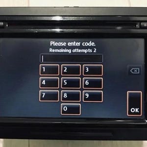 以下が含まれることがあります： デジタルディスプレイを備えた黒いカーオーディオシステム。画面には、数字キーパッドとファンクションボタンを使用してコードを入力するように求められます。画面のテキストは「コードを入力してください。残り試行回数2」と表示されています。