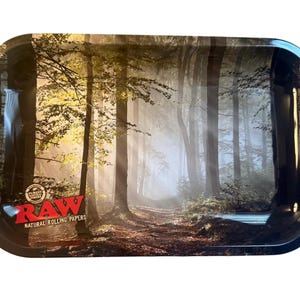 May include: Rectangular metal rolling tray with a forest scene. The tray features a path through a misty forest with tall trees and sunlight. The RAW logo is in red and white in the lower left corner.