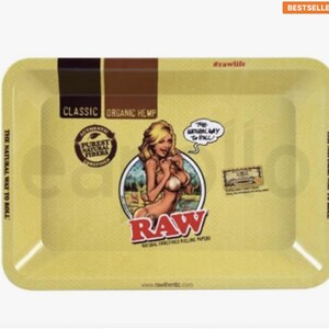Pu&ograve; includere: Vassoio rettangolare giallo con angoli arrotondati. Il vassoio presenta il testo "CLASSIC ORGANIC HEMP" e "RAW" in rosso. Un'illustrazione in stile pin-up &egrave; al centro. Il testo "THE NATURAL WAY TO ROLL" &egrave; stampato sui lati.