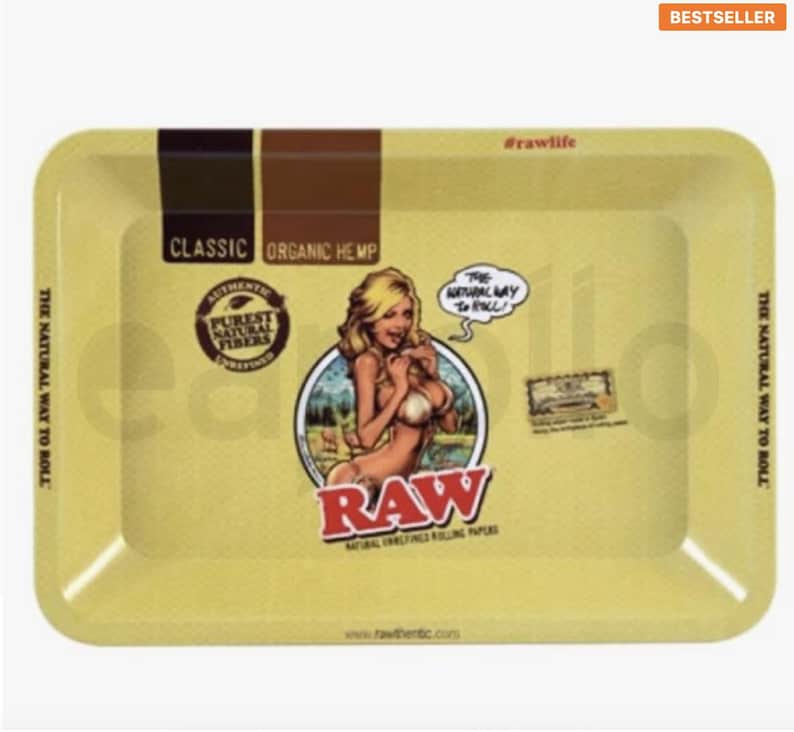 Pu&ograve; includere: Vassoio rettangolare giallo con angoli arrotondati. Il vassoio presenta il testo "CLASSIC ORGANIC HEMP" e "RAW" in rosso. Un'illustrazione in stile pin-up &egrave; al centro. Il testo "THE NATURAL WAY TO ROLL" &egrave; stampato sui lati.