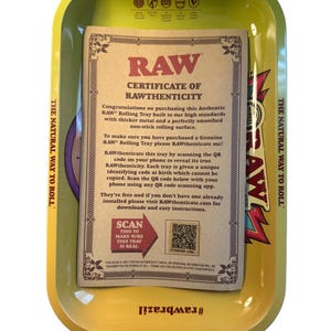 Puede incluir: Una bandeja para liar amarilla con un certificado de autenticidad. La bandeja tiene el texto "RAW" y "The Natural Way to Roll". El certificado incluye instrucciones para escanear un c&oacute;digo QR.