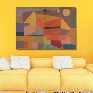 May include: Abstract geometric painting with a muted color palette of orange, brown, blue, and green. The artwork features a mountain-like composition with a sun and a dark circle in the upper portion. The painting is displayed above a yellow sofa.