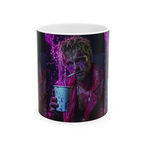 May include: White ceramic coffee mug featuring a vibrant, artistic design. The wrap-around image depicts a person with a cigarette, holding a cup, with a splash of purple liquid. The person is wearing a red jacket and has purple paint on their face.
