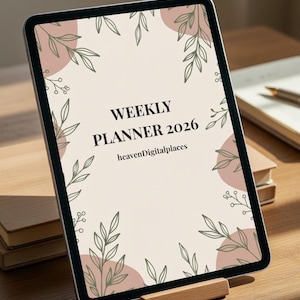 Può includere: Un tablet digitale che mostra un design "Weekly Planner 2026". Lo schermo ha uno sfondo beige con cerchi rosa e illustrazioni botaniche verdi. Il tablet è su un supporto di legno su una superficie di legno.