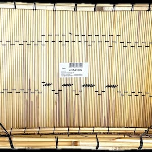 May include: A rectangular bamboo basket with a natural light brown color. The basket is constructed from vertical bamboo rods held together with black string. The label in the center reads "CHAJ BIG".