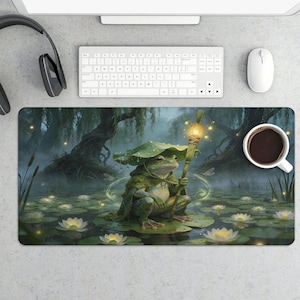 May include: A whimsical mousepad featuring a green frog in a cloak and hat, holding a glowing staff, sitting on a lily pad in a pond. The background shows a misty forest with glowing lights and lily pads. A cup of coffee is on the right.
