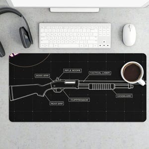 May include: Black mousepad featuring a white schematic of a shotgun with labeled parts like "rifle scope" and "handguard." A white coffee cup and computer accessories are visible.