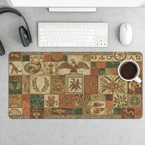 May include: Rectangular desk mat featuring a mosaic design with ancient Roman and Greek motifs. The mat has a patchwork pattern with images of eagles, columns, and other classical elements in shades of brown, green, and orange. A white coffee cup sits on the mat.