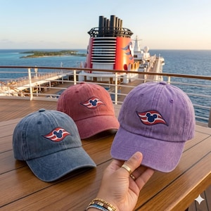 Op de afbeelding: Drie baseballpetten in blauw, rood en paars, elk voorzien van een geborduurd logo van een donkerblauw Mickey Mouse-silhouet op een gestileerd rood en wit golfontwerp. De petten hebben een verweerde stoftextuur en een gebogen klep.
