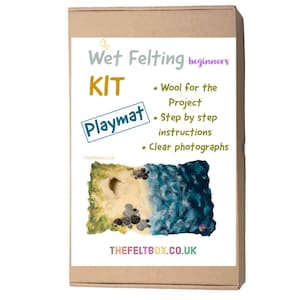 Può includere: Una scatola di cartone marrone con il testo "Wet Felting beginners KIT Playmat" sul davanti. La scatola contiene un kit di feltro a umido per realizzare un tappetino da gioco con una scena di spiaggia.