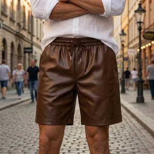 Può includere: Pantaloncini in similpelle marrone con elastico in vita e coulisse abbinata. I pantaloncini presentano una finitura liscia e semilucida, una vestibilità rilassata e arrivano a metà coscia. Il capo è abbinato a una camicia bianca a maniche lunghe.