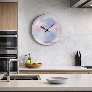 May include: A round wall clock with a white frame and a pastel sky design. The clock face features a gradient of pink, blue, and purple hues, with black hands and the numbers 12, 3, 6, and 9. The clock is mounted on a light gray wall.
