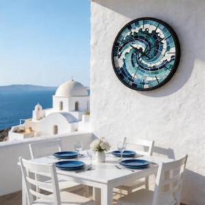 May include: A white outdoor dining set with a table and four chairs, set for a meal. A mosaic wall clock with a wave design hangs on the white wall. The background features a church and the sea.