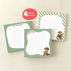 May include: Four square notepads with unique designs. One notepad has the text "Lily's swamp notes", another says "Lily's frog era", and a third says "ribbit, says Lily". Each notepad has a different border design and a mushroom-themed illustration.