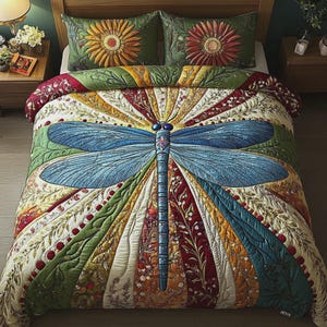 May include: A quilted bedspread featuring a large blue dragonfly design. The quilt has a colorful, patchwork-style background with floral and botanical patterns. Two matching pillow shams with flower designs complete the bedding set.