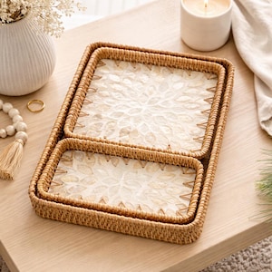 Puede incluir: Dos bandejas rectangulares tejidas, una dentro de la otra, con un estampado floral en el interior. Las bandejas son de color marrón claro y se encuentran sobre una superficie de madera clara. Una vela y un jarrón están en el fondo.