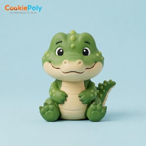 May include: A small, green, cartoon-style alligator figurine with a cream-colored belly, large dark eyes, and textured scales on its head and back. The figure is in a seated position with its arms resting on its stomach and a visible tail.